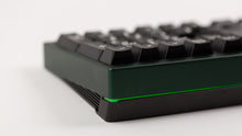 Load image into Gallery viewer, green case featuring white on black keycaps close up back right view