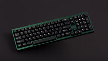 Load image into Gallery viewer, green case featuring white on black keycaps angled