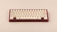 Load image into Gallery viewer, Beetle 60 in maroon with keycaps on a beige background