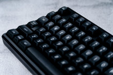 Load image into Gallery viewer, GMK MTNU WoB black keycaps on white keyboard, front profile view showing MTNU sculpt on dark wood