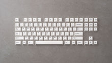 Load image into Gallery viewer, GMK CYL BoW white keycaps with black legends arranged in TKL layout on gray concrete surface