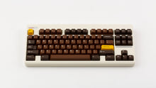 Load image into Gallery viewer, GMK CYL Chocolatier keycaps on cream NK Classic TKL keyboard, full angled view with golden Esc and Golden Ticket accent keys