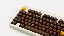 Load image into Gallery viewer, GMK CYL Chocolatier keycaps on cream NK Classic TKL keyboard, close-up of top-left corner showing golden Esc key
