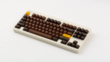 Load image into Gallery viewer, GMK CYL Chocolatier keycaps on cream NK Classic 75% keyboard, full angled view with golden Esc and Golden Ticket accent keys