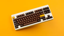 Load image into Gallery viewer, GMK CYL Chocolatier keycaps on cream NK Classic TKL keyboard against orange background, full angled view