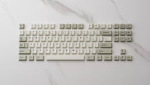Load image into Gallery viewer, GMK CYL Classic Beige keycaps with gray modifiers arranged in TKL layout on white marble surface
