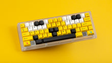 Load image into Gallery viewer, GMK CYL GREG 2 keycaps on a transparent 60 percent keyboard against a yellow background, full view