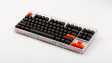 Load image into Gallery viewer, GMK CYL Kaiju R3 dark base keycaps on clear acrylic TKL keyboard, full board angled view