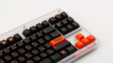 Load image into Gallery viewer, GMK CYL Kaiju R3 dark base keycaps close-up of right side, orange accents on clear keyboard