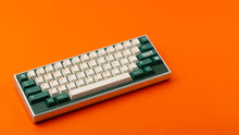 Load image into Gallery viewer, GMK CYL Kaiju R3 hiragana base keycaps on silver 65% keyboard on orange background, angled view