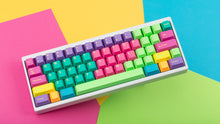 Load image into Gallery viewer, GMK CYL Windbreaker keycaps on white 65% keyboard on colorful background, top-down angled
