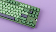 Load image into Gallery viewer, GMK CYL Zooted keycaps on green 1800 compact keyboard, close-up of right side showing navigation cluster, purple Enter accent key, and leaf novelty keycap on lavender background