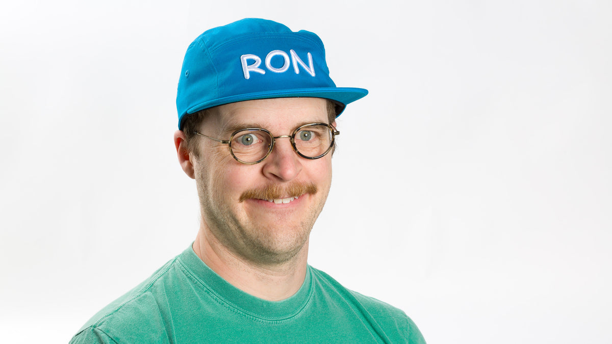  model smiling wearing a Blue Ron Hat 