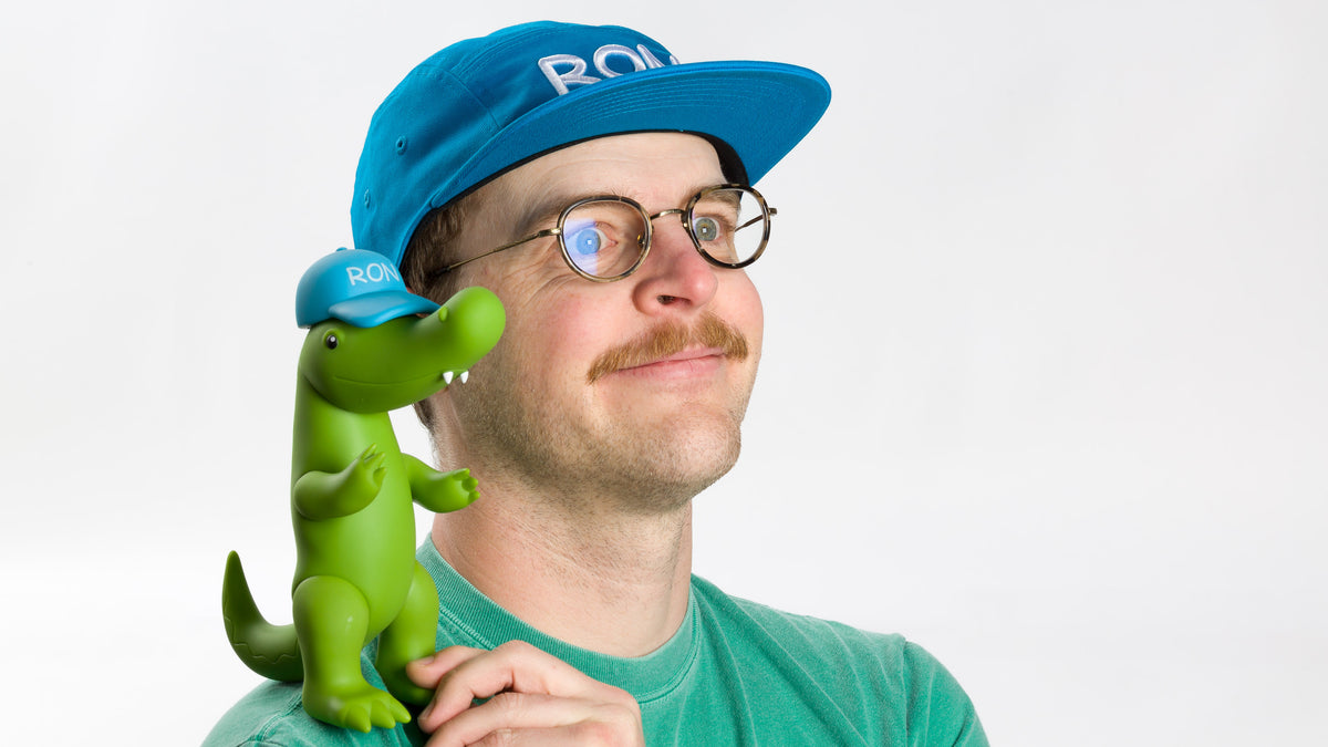  model posing with a vinyl ron on his shoulder wearing a Blue Ron Hat 