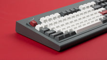 Load image into Gallery viewer, Smurve80 keyboard in Graphite left side angle showing smile logo on red surface