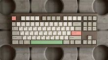 Load image into Gallery viewer, Render of GMK CYL Classic Beige keycaps with pink and green accents on dark bronze TKL keyboard, top-down view on concrete background