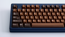 Load image into Gallery viewer, Render of GMK CYL Chocolatier keycaps on a keyboard, angled product view highlighting the chocolate and golden color scheme