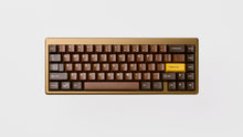 Load image into Gallery viewer, Render of GMK CYL Chocolatier keycaps on a white 65% keyboard, full angled view showing chocolate brown alphas and golden accent keys