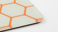 Load image into Gallery viewer, Close-up of the NovelKeys Glasspad corner showing the tempered glass edge and orange honeycomb etching