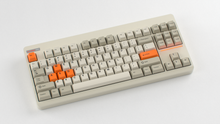 Load image into Gallery viewer, Render of GMK CYL Mini Orange Accent Pack keycaps on beige Classic TKL keyboard, wide angle view
