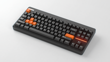 Load image into Gallery viewer, Render of GMK CYL Mini Orange Accent Pack keycaps on black Classic TKL keyboard, wide angle view